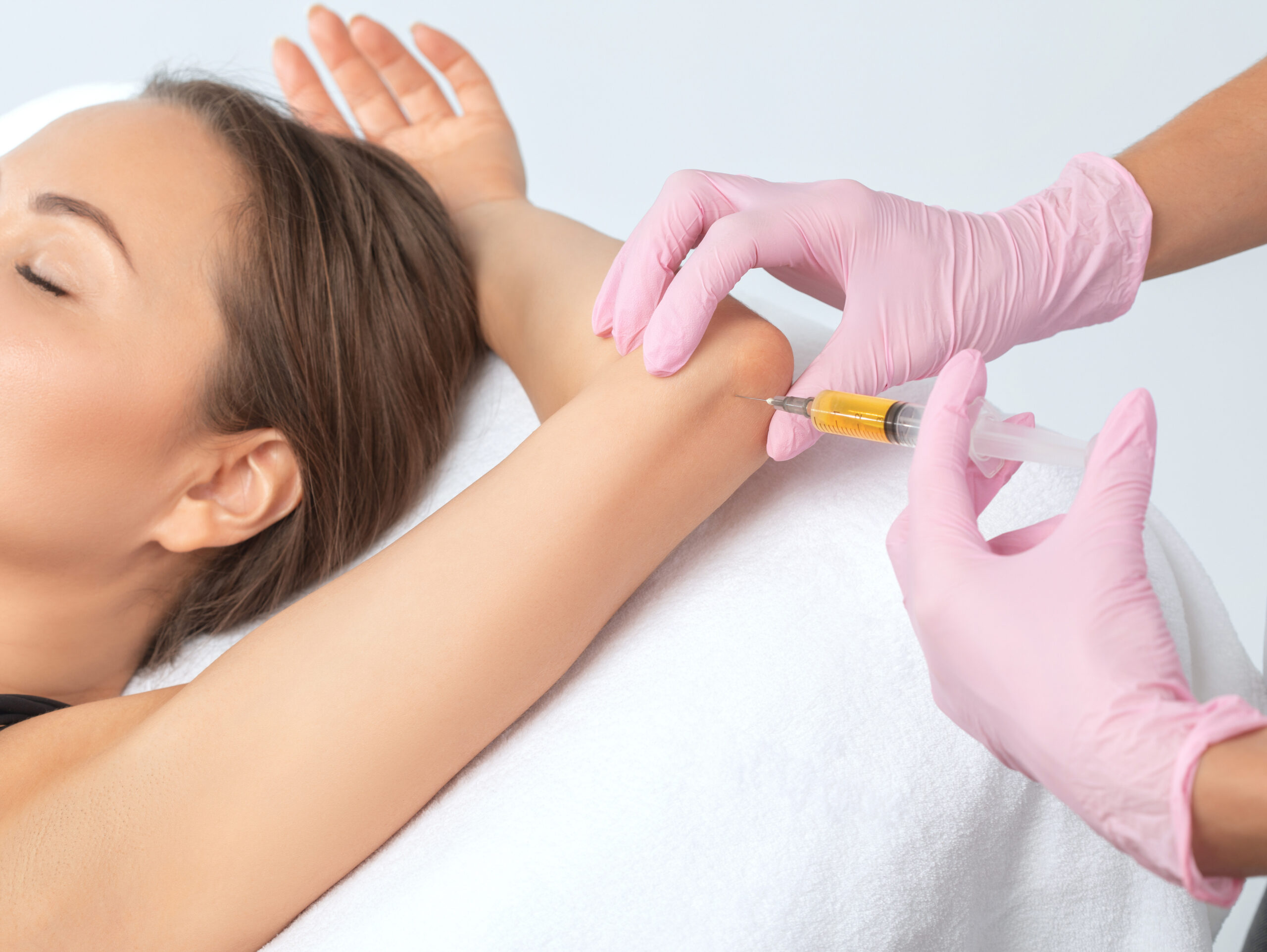 Doctor doing stem cell therapy on a patient's elbow after the injury. Treating knee pain with platelet-rich plasma injection. Treatment of arthritis and osteoarthritis.Medical and cosmetology concept.